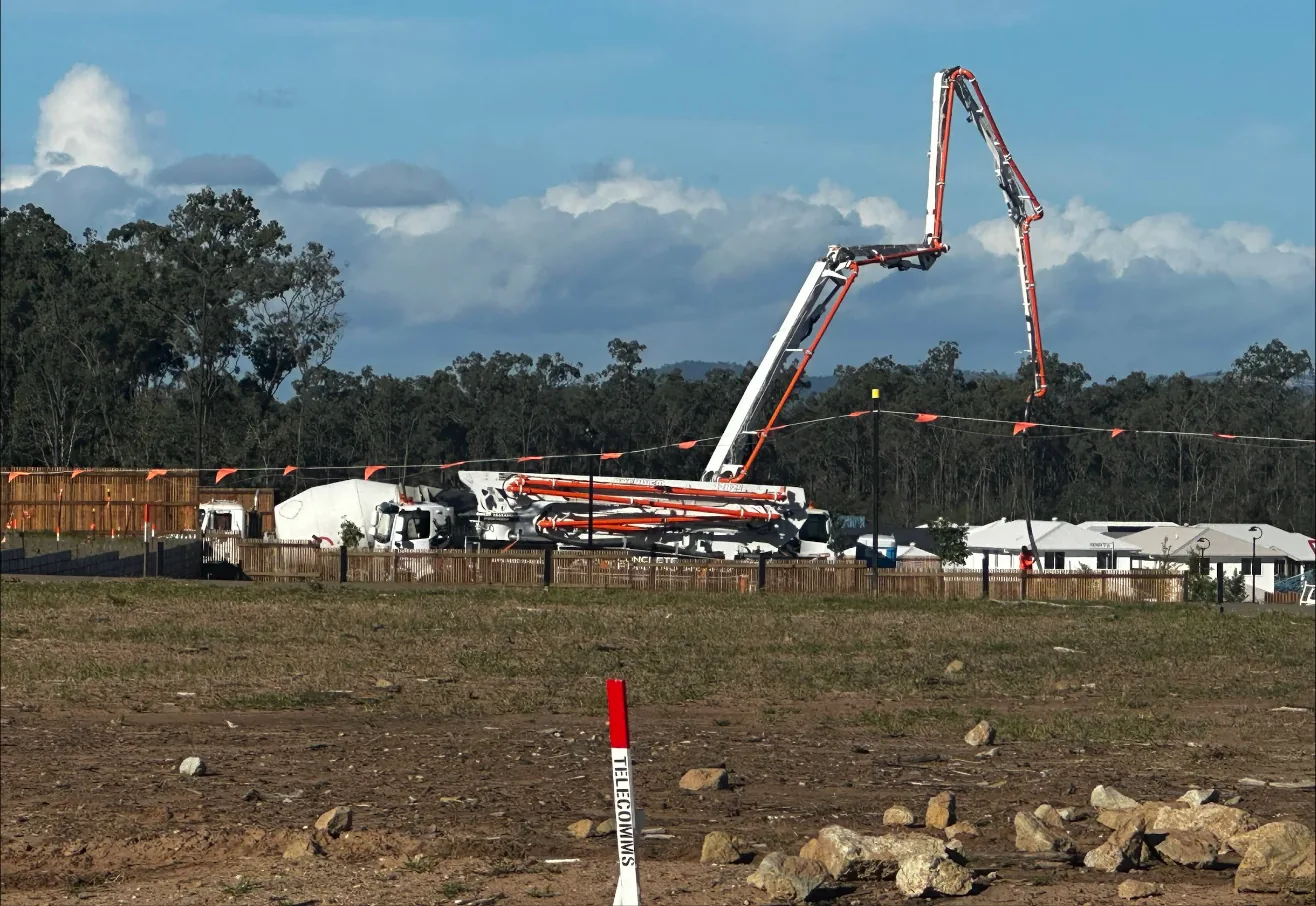 A concrete pump pouring a slab on a new lot