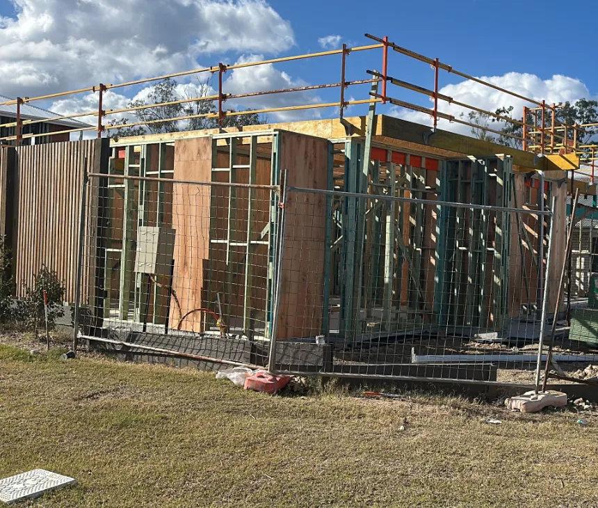 A frame going up behind temporary fencing