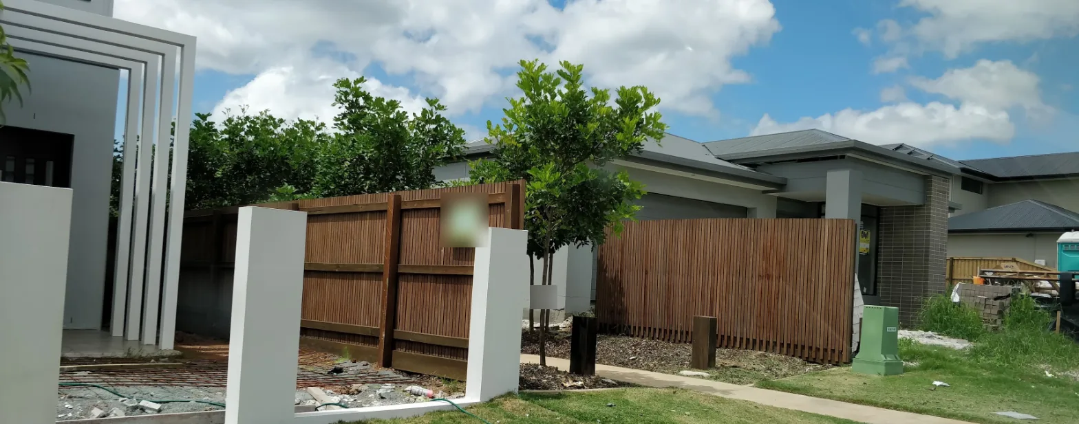 A timber slat front fence with rendered pillars being built