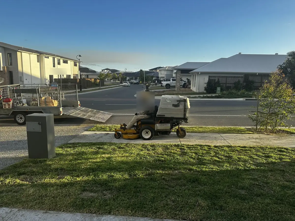 A ride-on mower finishing a freshly cut front lawn