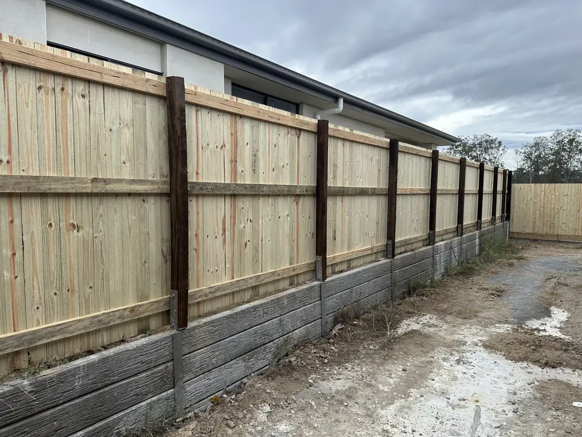 A timber fence built on a concrete sleeper retaining wall