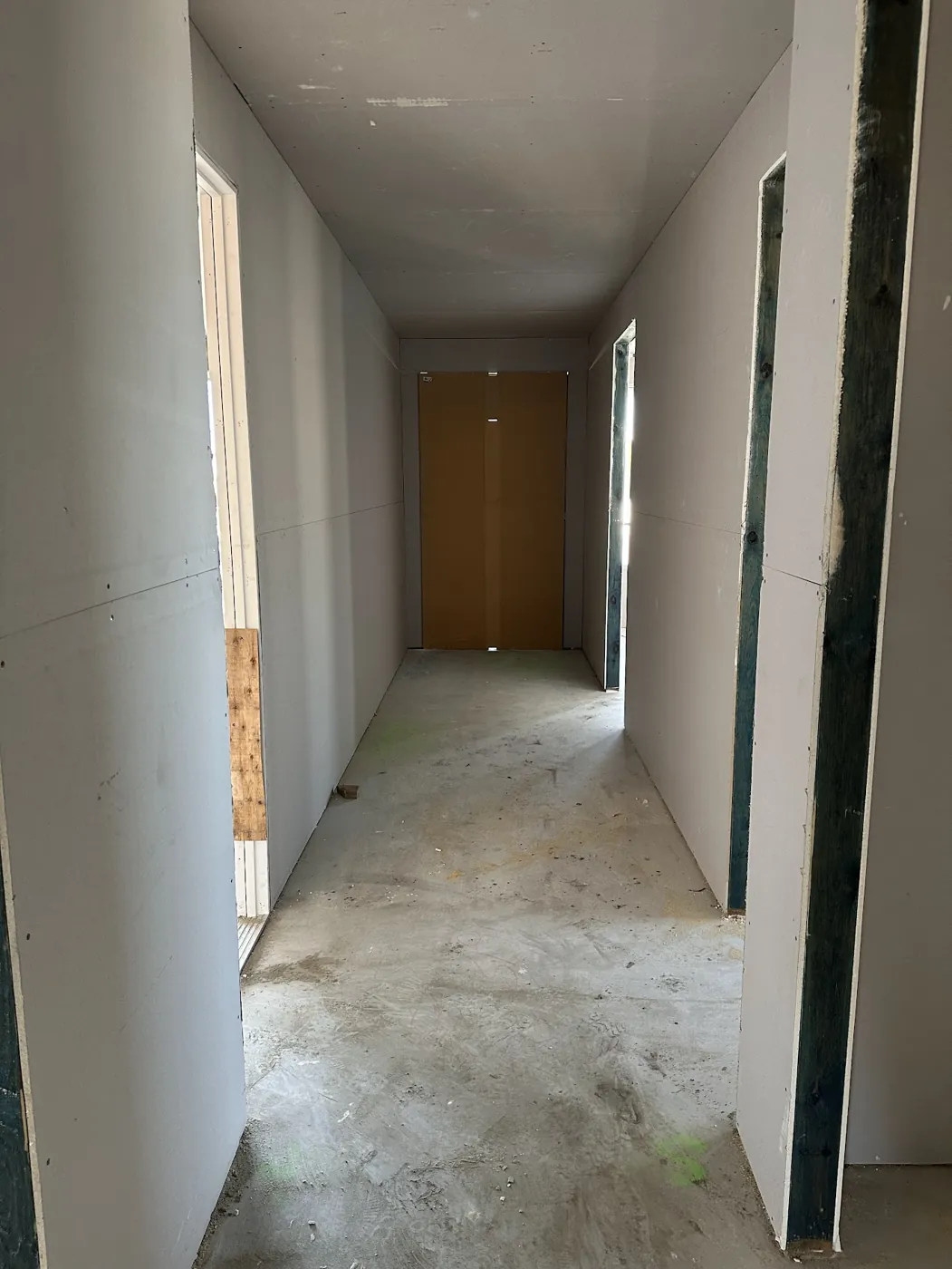 An unfinished hallway with plasterboard walls and doors