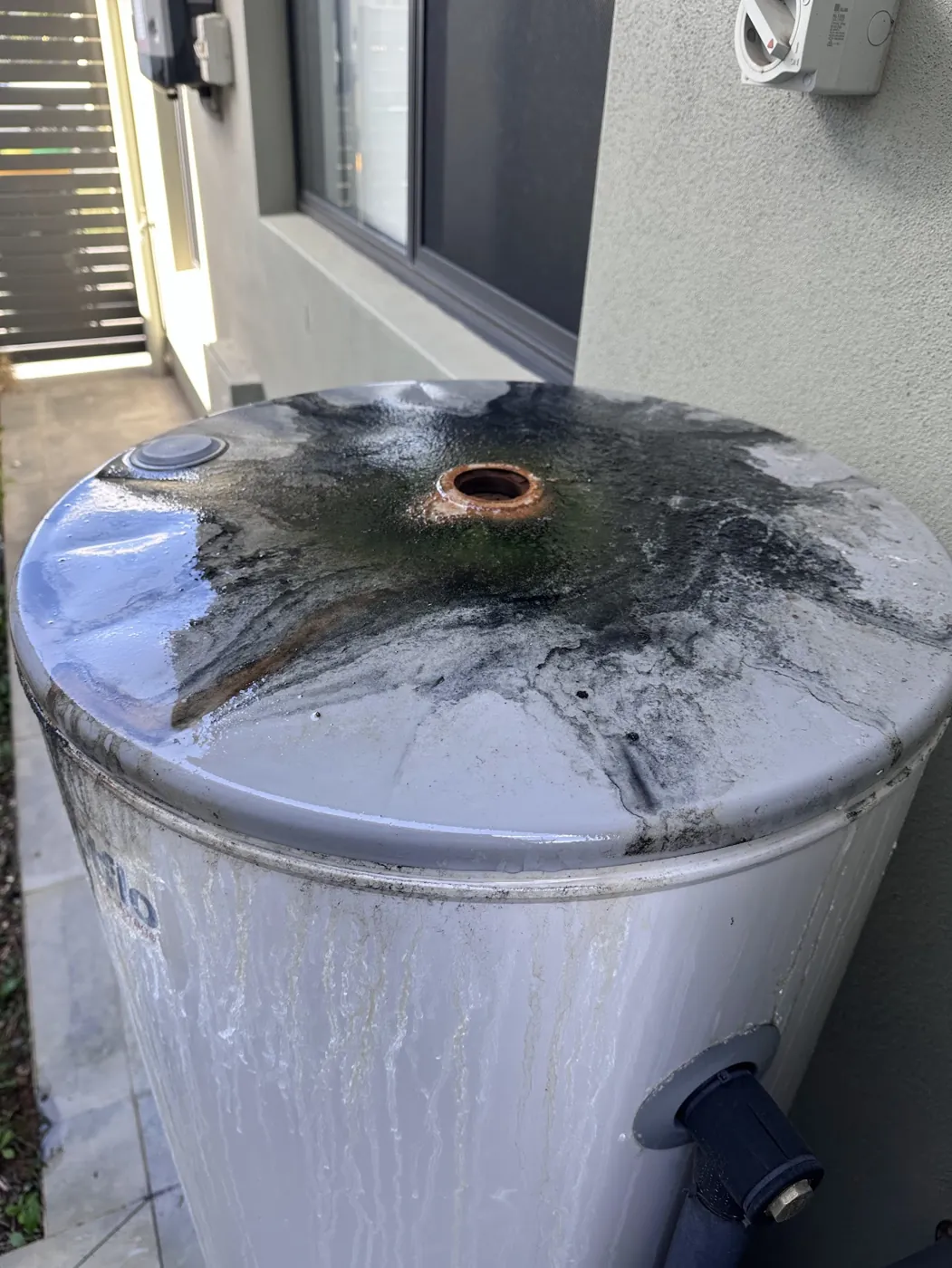 Top of a hot water tank with corrosion and rust around the outlet