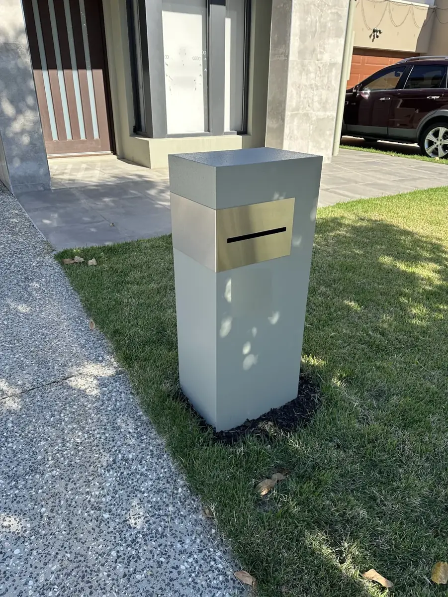 A modern pillar letterbox on a front lawn
